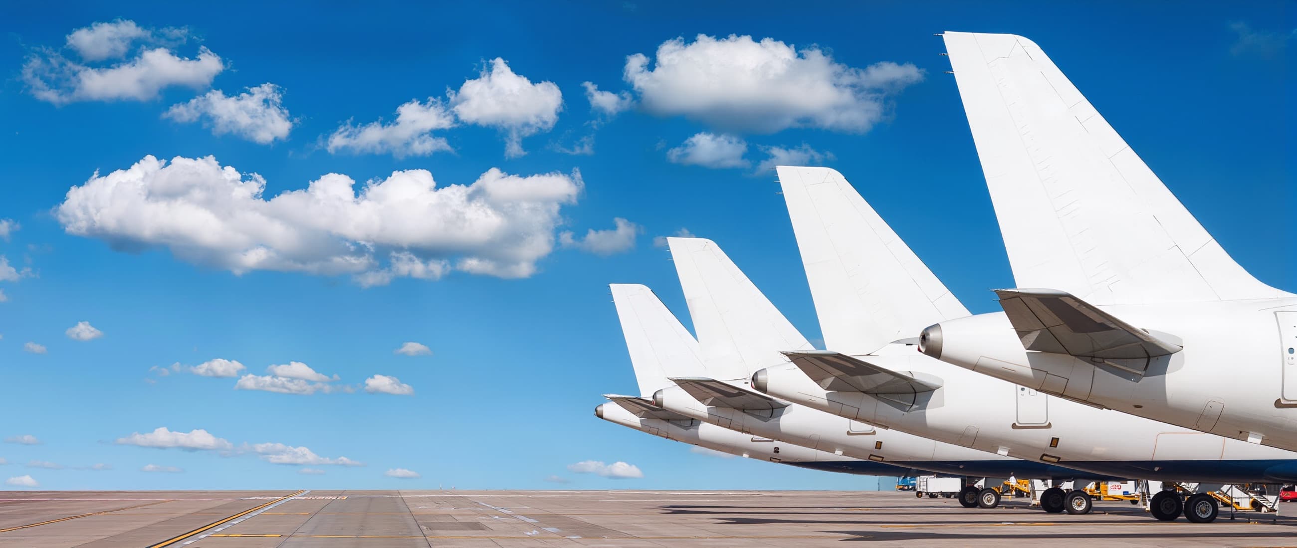 Row of white airliner tails lined up at the terminal.